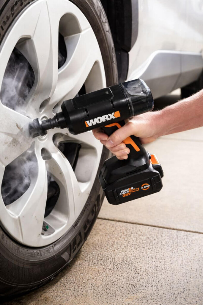 Worx 20V SteamStorm cordless steam cleaner removing dirt and brake dust from a car wheel rim using concentrated steam