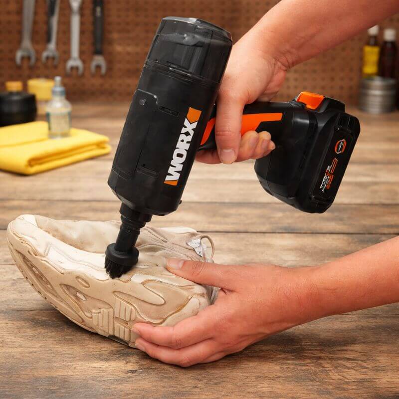 Worx 20V SteamStorm cordless steam cleaner scrubbing a dirty sneaker with a brush attachment